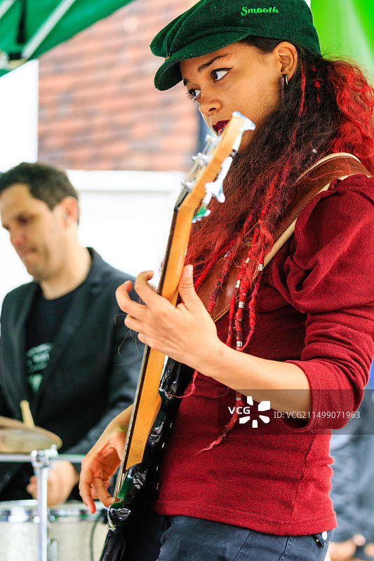 法国民谣摇滚乐队Triskelles的摇滚音乐家Reden在露天演出中用乐队演奏电贝斯，侧视特写镜头图片素材