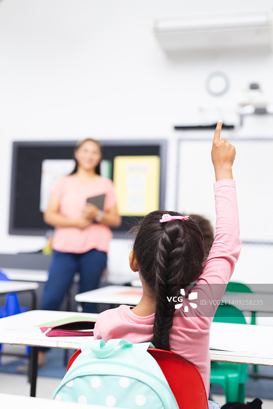混血女教师手持平板电脑，学生举手，预留文案空间图片素材