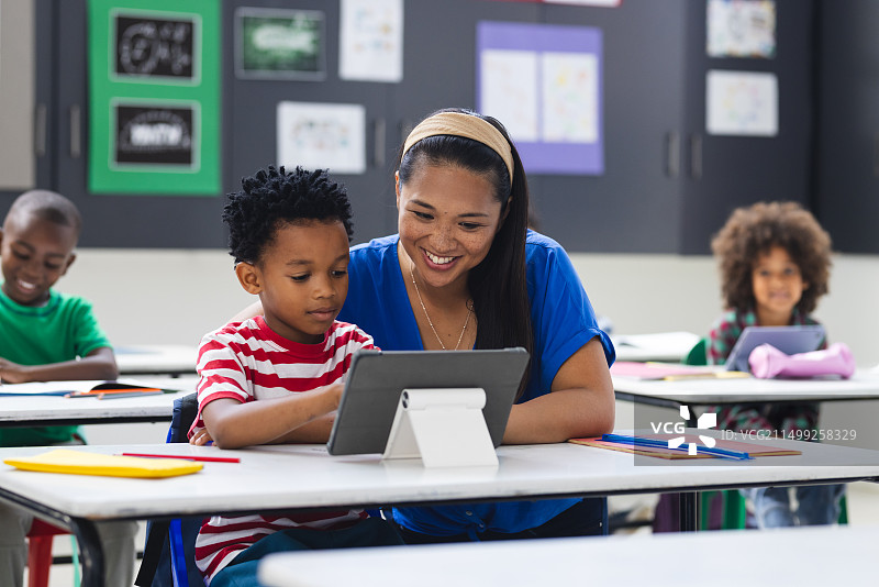 在学校里，年轻的非洲裔美国男孩和女人正在教室里看平板电脑图片素材
