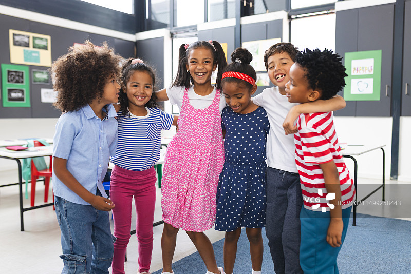 在学校里，一群年轻学生在教室里拥抱欢笑图片素材