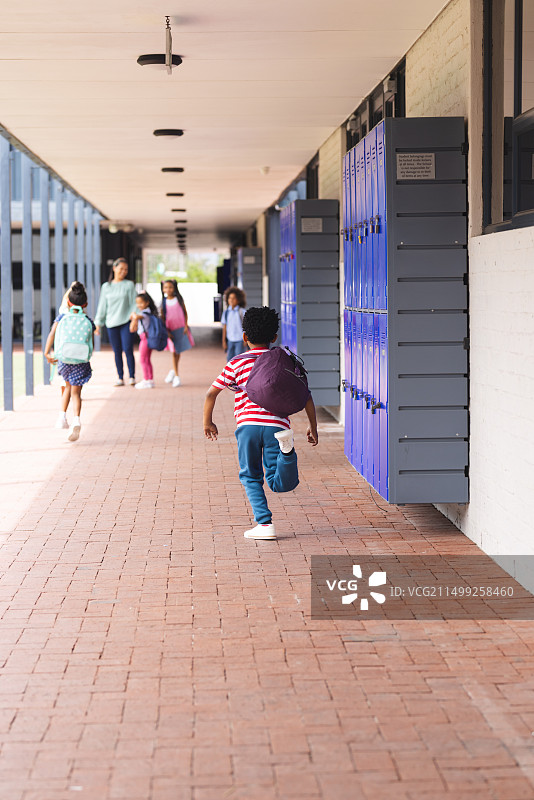 学校里，不同的孩子走在有储物柜的走廊上图片素材