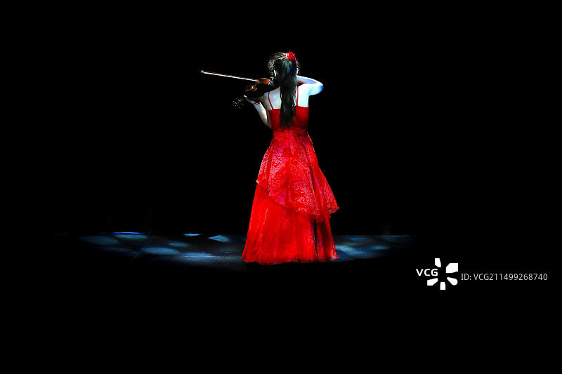 穿红裙的年轻女小提琴手在舞台上图片素材