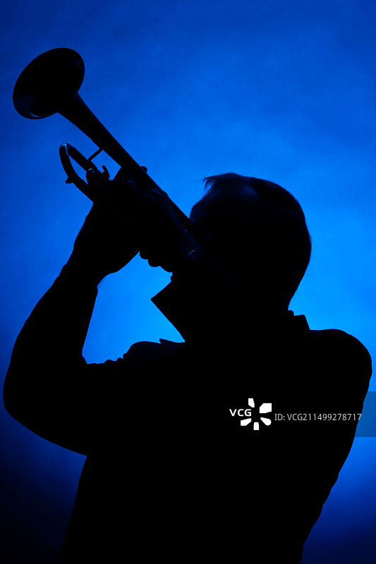 竖版蓝色聚光灯下小号手剪影图片素材