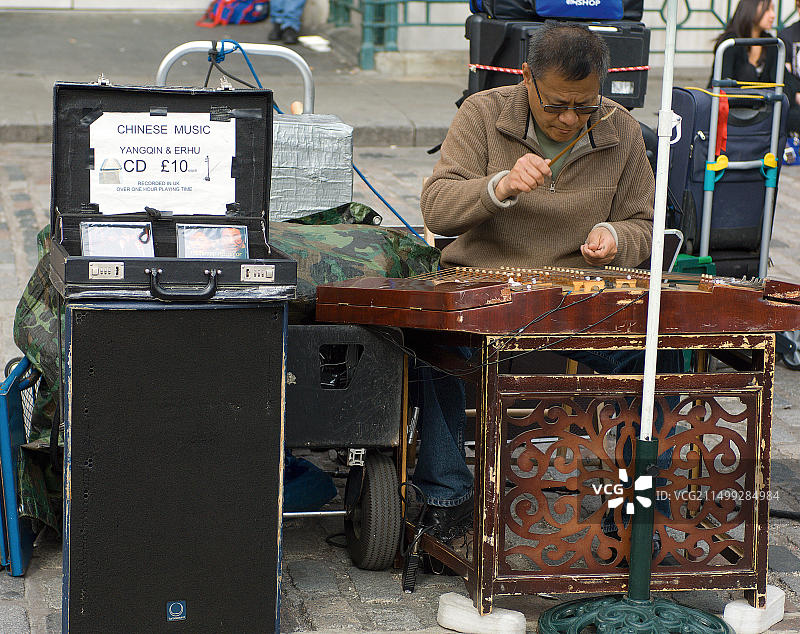 他出售的CD盒上解释说，这位音乐家正在演奏一种叫做扬琴的乐器图片素材