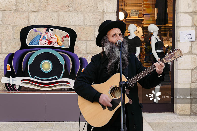 中东以色列耶路撒冷马哈尼·耶胡达市场，犹太男子弹吉他招待购物者图片素材