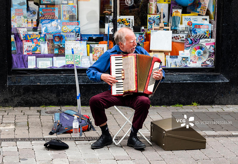 老年男性街头艺人在爱尔兰戈尔韦市High Street演奏手风琴图片素材