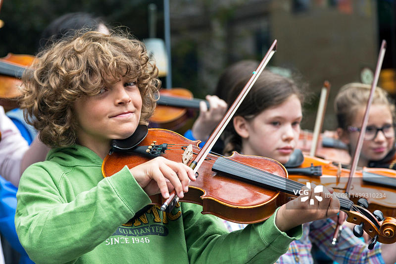 来自格拉斯哥盖尔语学校的11岁学生Robby Whyte与其他学生一起在格拉斯哥街头卖艺图片素材