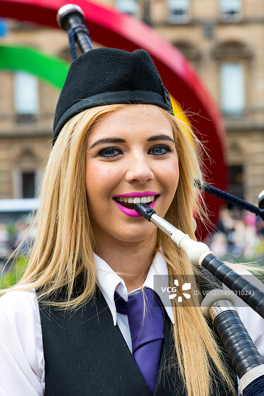 来自格拉斯哥的18岁女孩克里斯蒂娜·麦克唐纳在格拉斯哥英联邦标志前演奏风笛图片素材