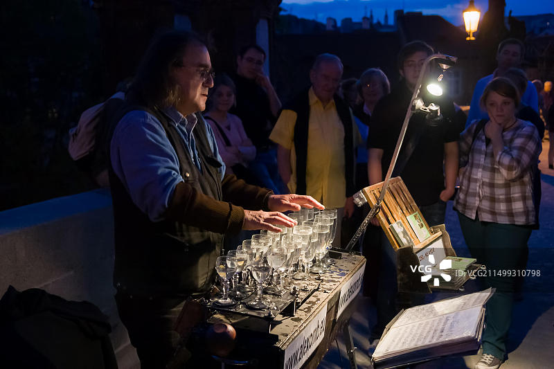 在捷克共和国布拉格市的夜晚，人们在欣赏亚历山大·佐尔坦的玻璃杯音乐表演图片素材
