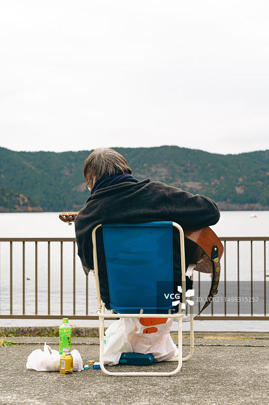 一位老人在箱根芦之湖边弹吉他图片素材