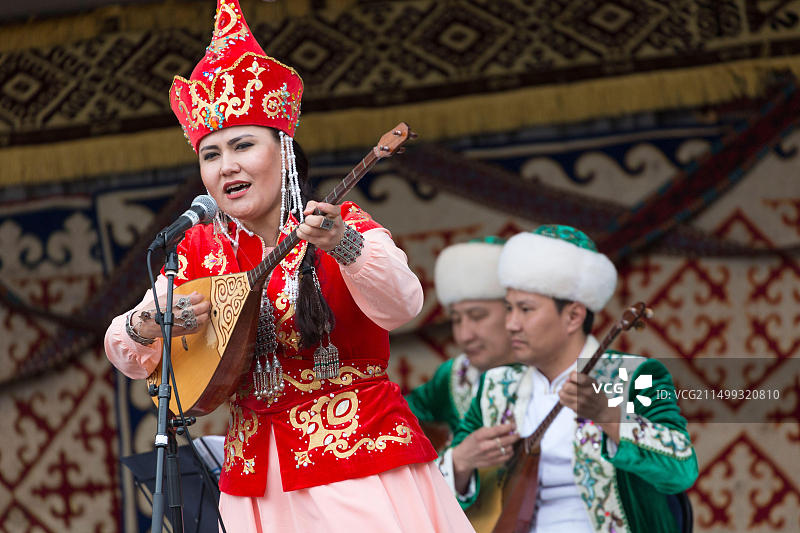 在伦敦维多利亚堤岸花园哈萨克斯坦春节上，一位哈萨克斯坦妇女在舞台上唱歌和演奏冬不拉的画像图片素材
