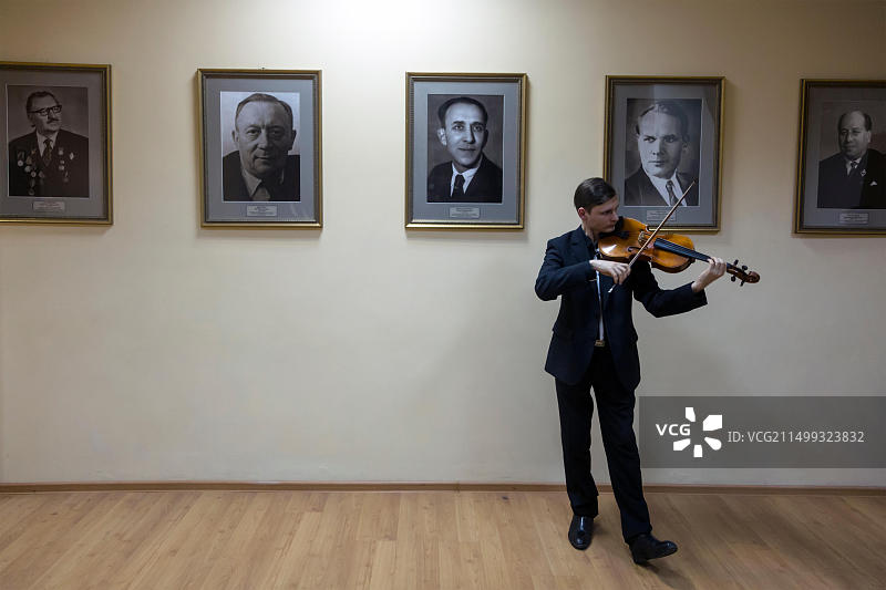 俄罗斯格涅辛音乐学院，学生在著名学者肖像的背景下排练小提琴，莫斯科图片素材