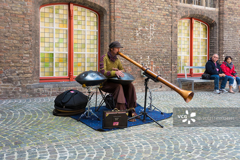在比利时布鲁日市场大厅内院演奏钢鼓和迪吉里杜管的街头艺人图片素材