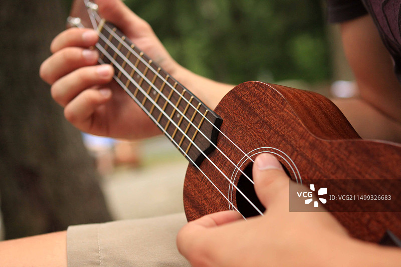 两只手弹奏木制尤克里里的照片图片素材