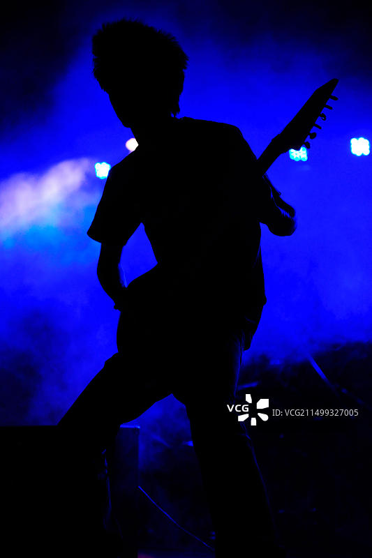 印度音乐会上蓝色背景的摇滚吉他手剪影图片素材