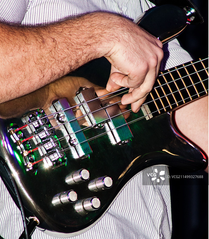 男贝斯手在黑色背景上演奏图片素材