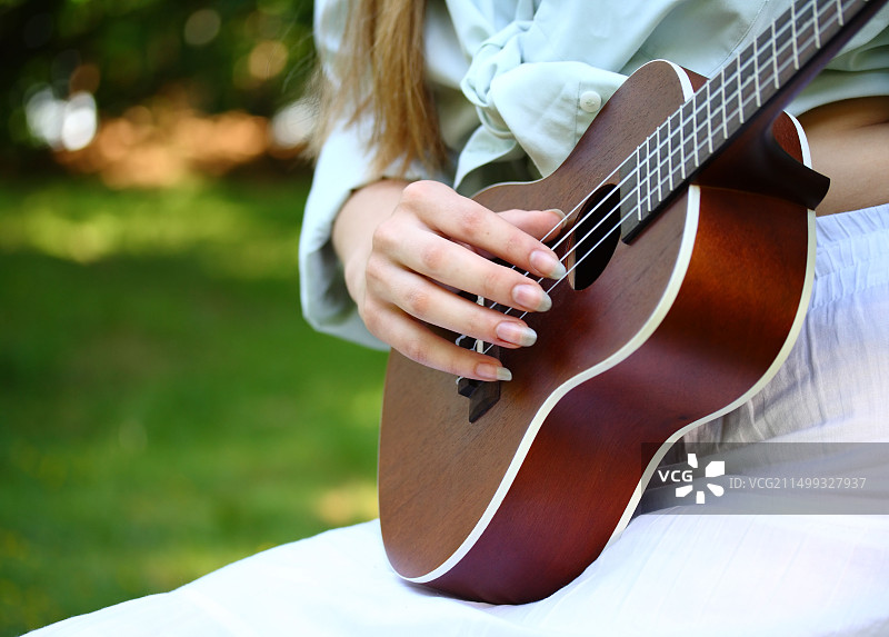 原声吉他和绿色背景上的女人手部特写图片素材