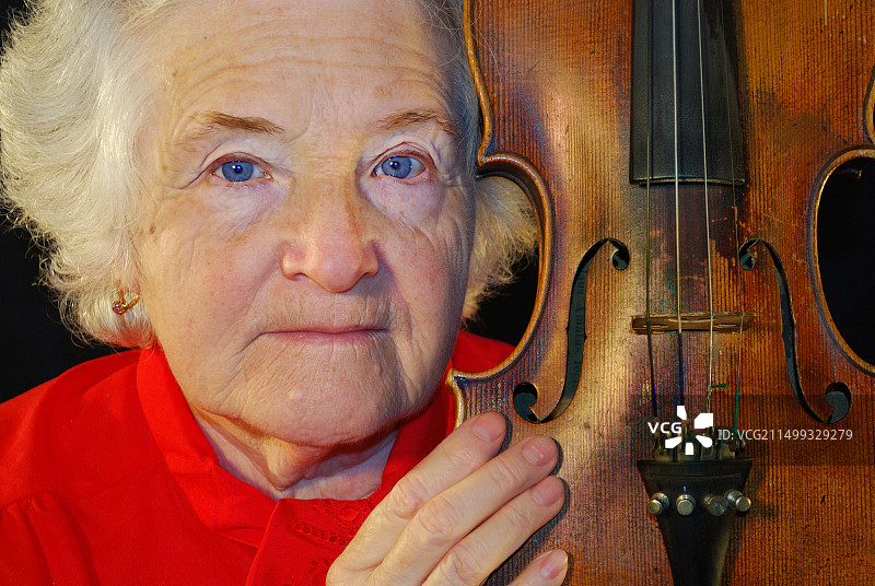 手持古老小提琴的红衣老年妇女肖像图片素材