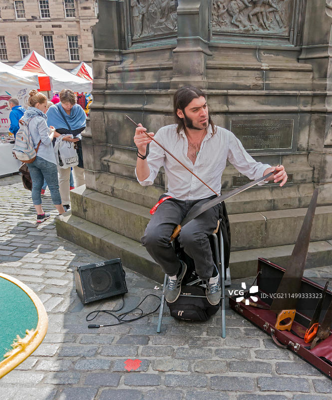 音乐人在爱丁堡皇家一英里举行的2015年爱丁堡边缘艺术节上推广锯琴演奏图片素材
