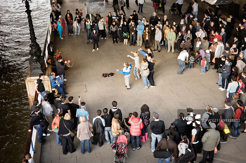 一群女孩随着街头艺人的音乐跳舞图片素材