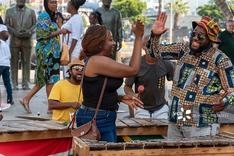 南非开普敦：街头音乐家在中央海滨区与游客互动，女子与乐队成员互动图片素材