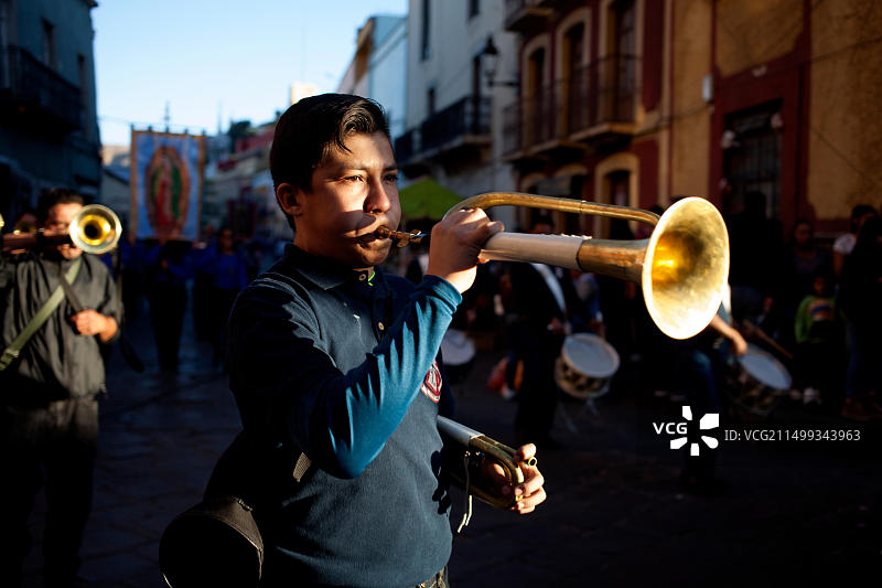在墨西哥瓜纳华托，一名男子在游行中演奏短号，纪念瓜达卢佩圣母图片素材
