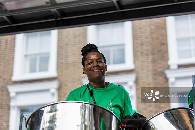 年轻黑人女性在诺丁山街头狂欢节上，作为钢乐队的一员，在浮动平台上敲击油桶鼓图片素材