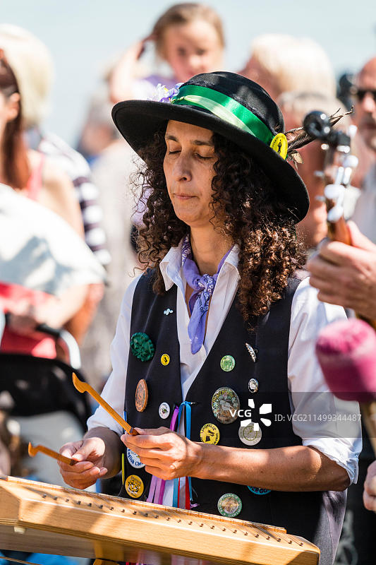 布罗德斯泰斯民俗周：芒特莫里斯舞者和扫帚舞者，戴黑帽的女子在户外演奏木琴，后方有观众图片素材