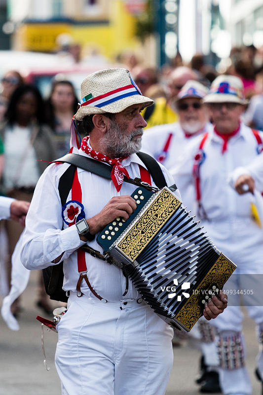 中年男子手风琴演奏者带领哈特利莫里斯舞蹈队在城镇街道游行图片素材