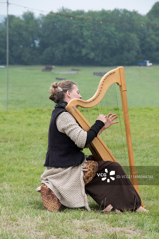 英国威尔士切普斯托 The Green Gathering 音乐节，一位女士独自在宁静的早晨弹奏竖琴图片素材