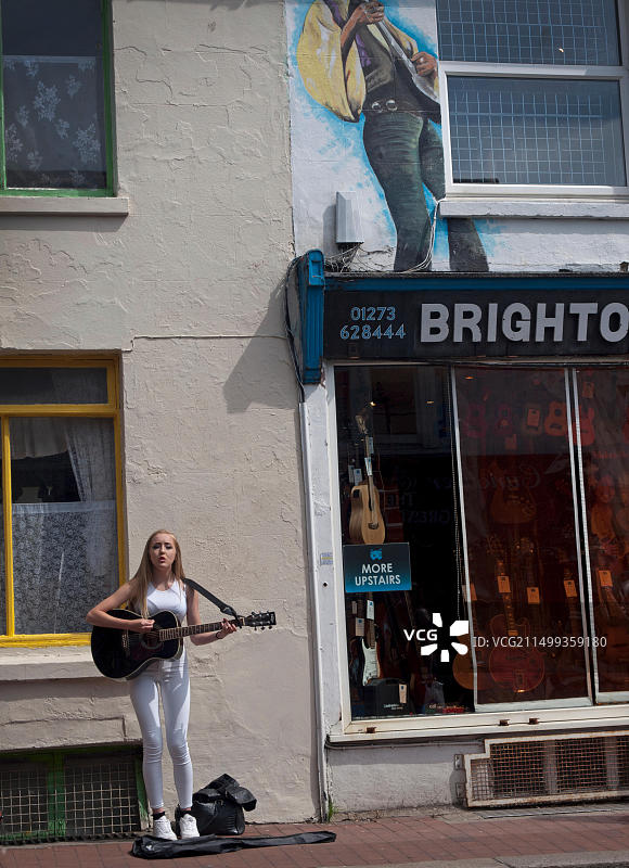 一个年轻女孩在布莱顿的后街卖艺图片素材