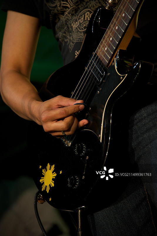 摇滚音乐家演奏黑色吉他的特写图片素材