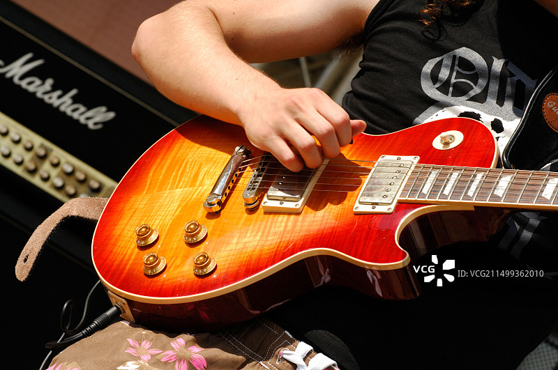 音乐家弹奏电吉他的特写，展示了指板拾音器和放大器图片素材