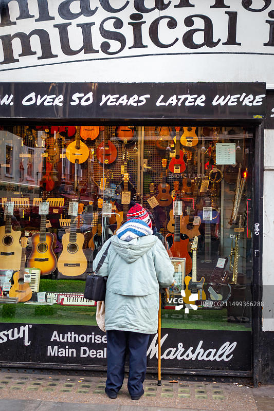 年长的女士在伦敦查令十字路观看著名的马卡里斯乐器店图片素材