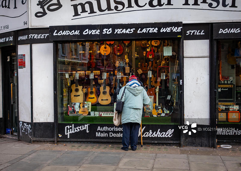 年长的女士在伦敦查令十字路观看著名的马卡里斯乐器店图片素材
