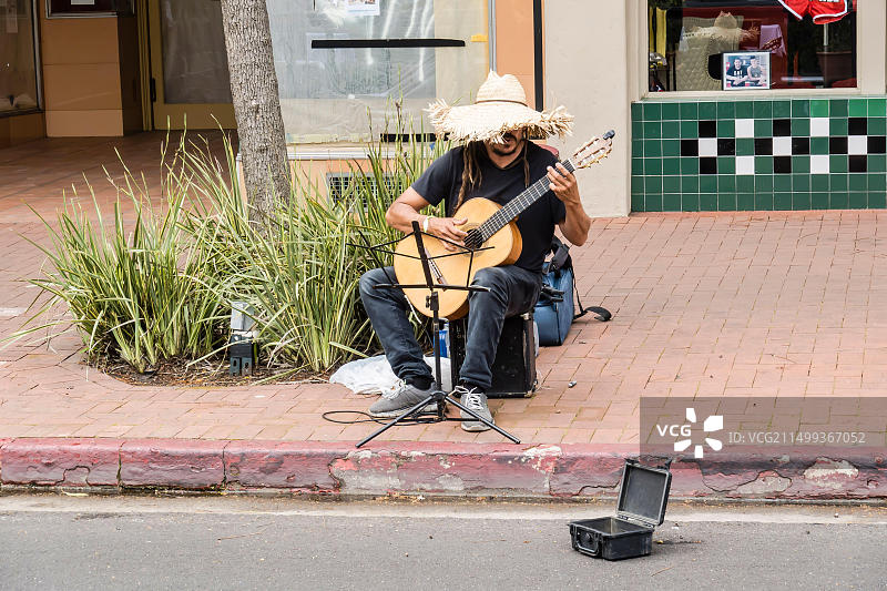 独自一人在加利福尼亚州圣巴巴拉州立街的人行道上演奏吉他的男人图片素材