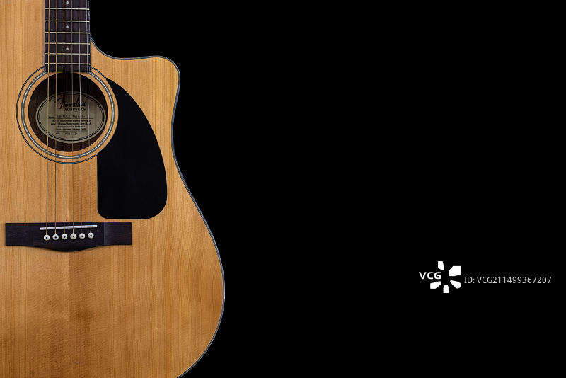经典黄色原声吉他Fender CD-60的琴身部分，带黑色护板，黑色背景留有文字空间图片素材