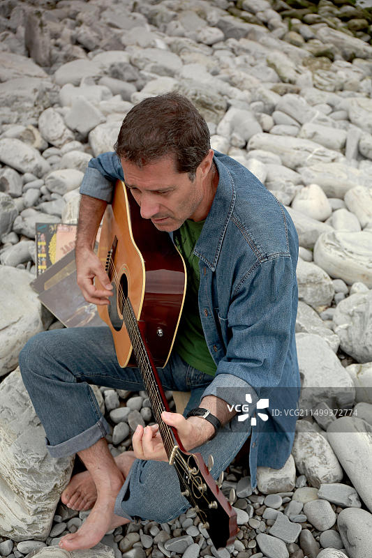 在岩石上弹吉他的吉他手图片素材