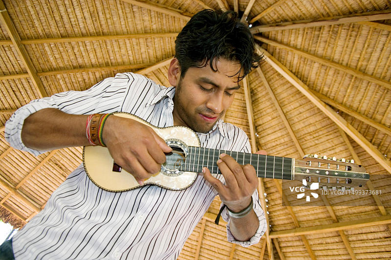 在玻利维亚凉亭下演奏安第斯传统弦乐器查兰戈琴的条纹衬衫青年图片素材