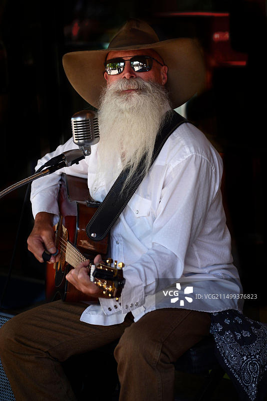 新墨西哥州圣菲市的街头音乐家约翰尼·劳埃德在人行道上表演图片素材