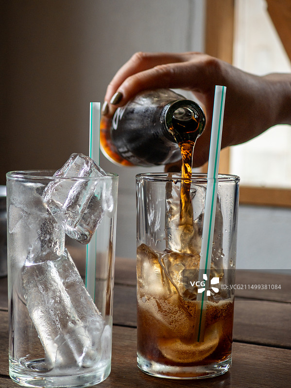 往装着冰块的玻璃杯里倒饮料图片素材