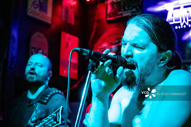摇滚乐队在舞台上表演，男歌手用麦克风演唱图片素材