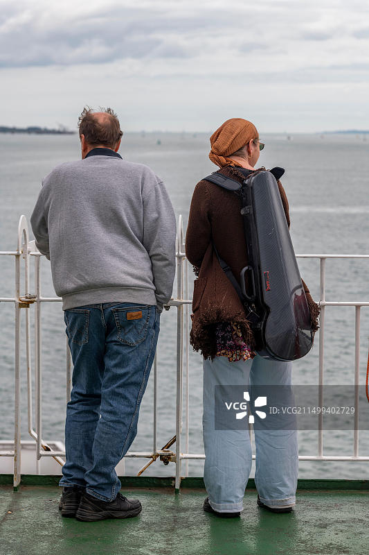 老年夫妇在海边眺望，女士携带小提琴盒图片素材