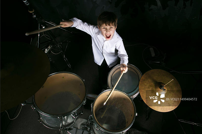 孩子打鼓，鼓组后面的男孩音乐家。图片素材