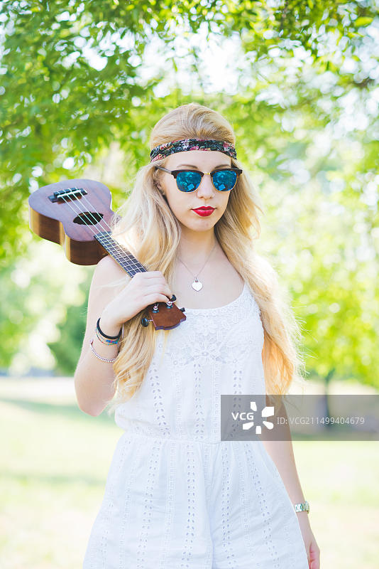 年轻漂亮的女人在户外城市公园弹奏尤克里里——音乐家、作曲家、街头艺人概念图片素材