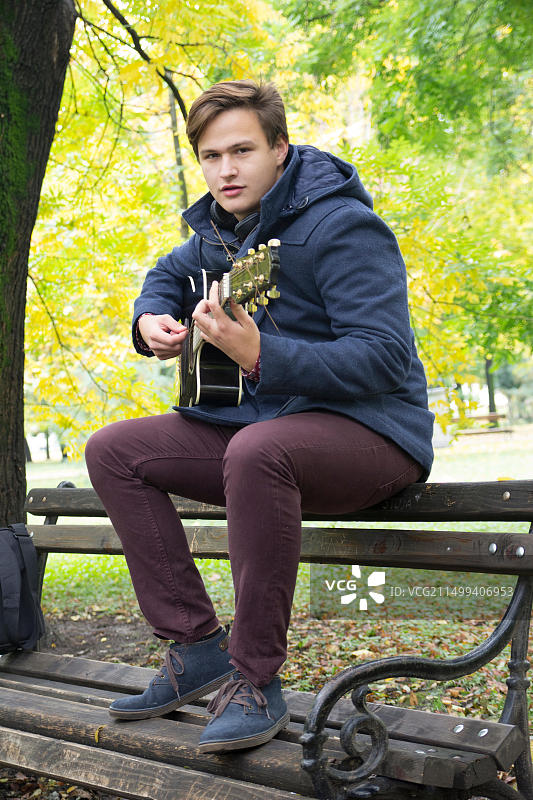 抱着原声吉他的年轻男人，选择性聚焦和小景深，镜头光晕图片素材