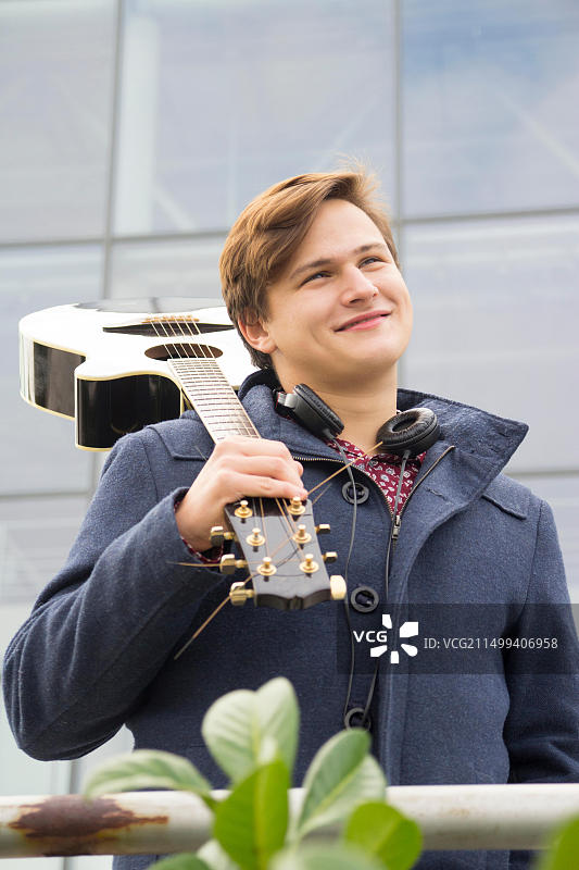 抱着原声吉他的年轻男人，选择性聚焦和小景深，镜头光晕图片素材
