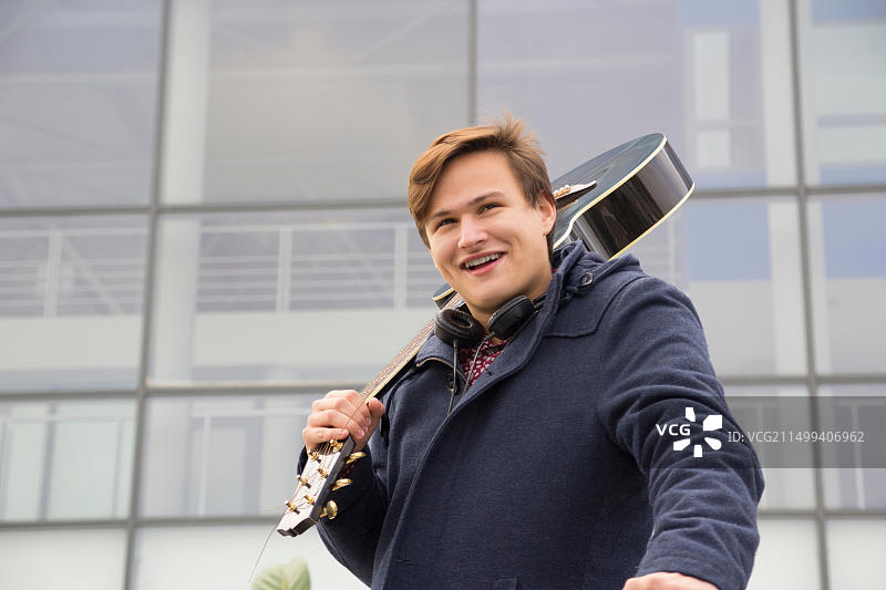 抱着原声吉他的年轻男人，选择性聚焦和小景深，镜头光晕图片素材