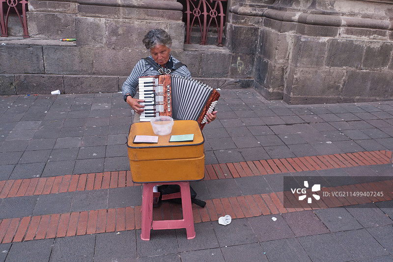 厄瓜多尔基多，一位盲人街头音乐家在街头简易桌子后演奏手风琴乞讨图片素材
