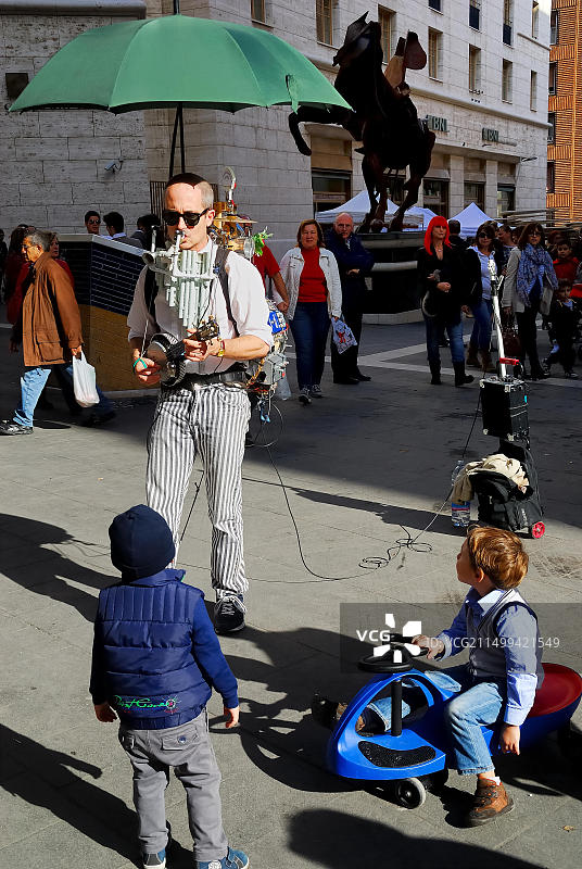 意大利那不勒斯：两个孩子在托莱多街听街头音乐家演奏图片素材